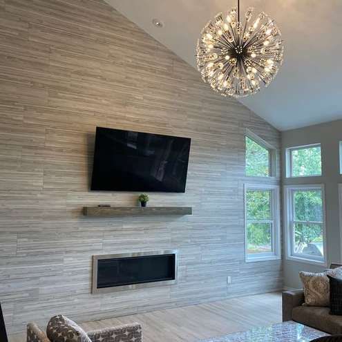 A living room with a fireplace , couch , television and chandelier.