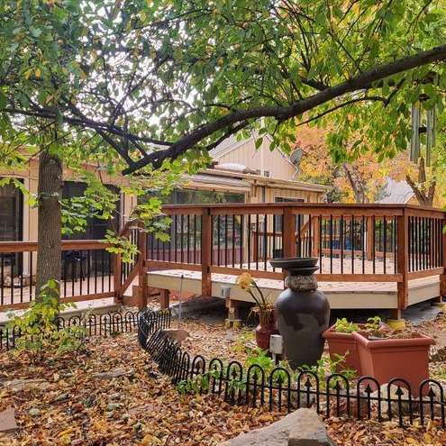 A wooden deck with a fence around it and a house in the background.