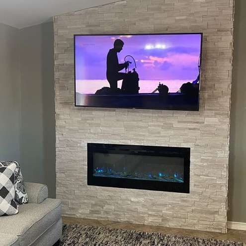 A living room with a fireplace and a flat screen tv on the wall.