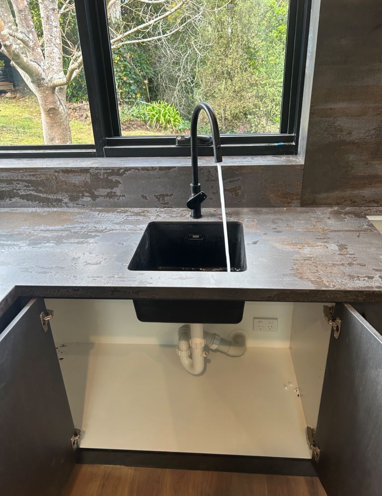 Modern Kitchen Sink With Black Faucet Above an Open Under-sink Cabinet — The Plumbing & Drainage Co. in Mittagong, NSW