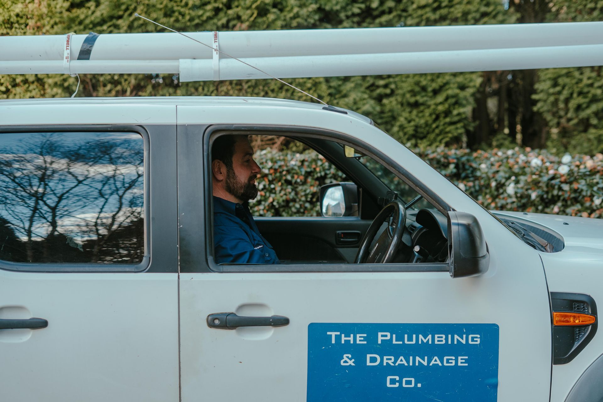 Person repairing a bathroom sink cabinet drawer under a white countertop. — The Plumbing & Drainage Co. in Mittagong, NSW