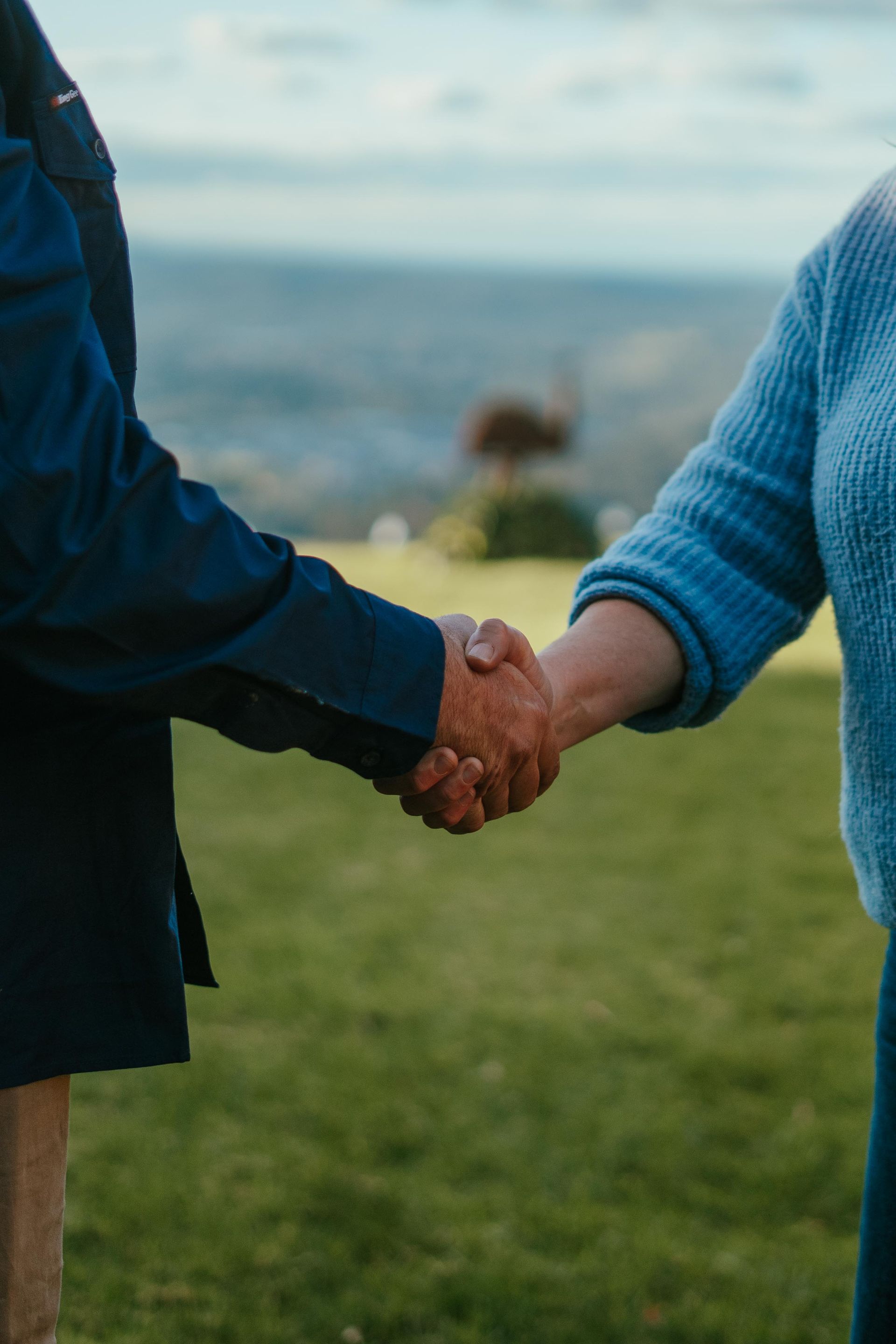 Two people holding hands outdoors near the ocean, wearing blue jackets and sweaters. — The Plumbing & Drainage Co. in Mittagong, NSW