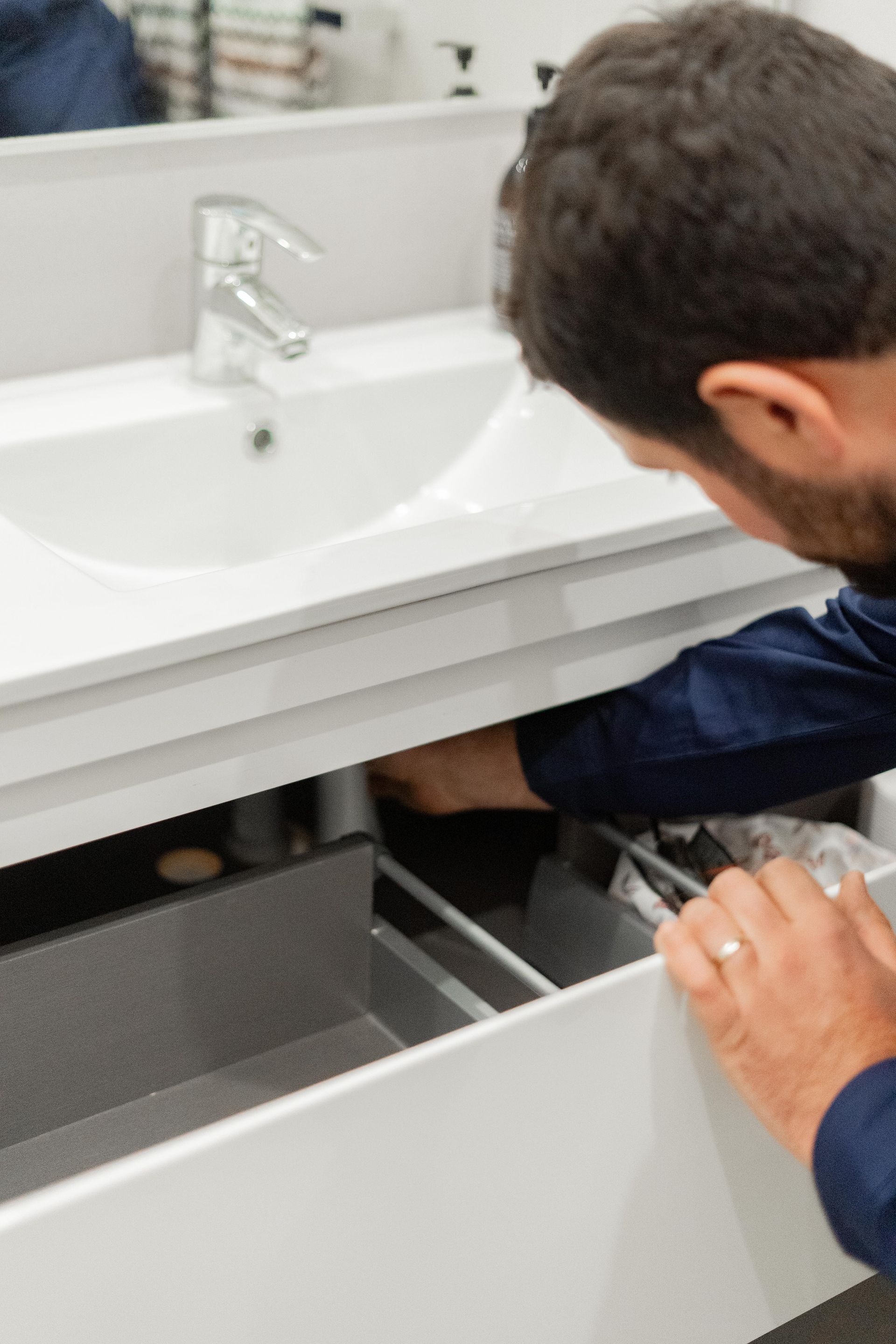 Person opening a bathroom vanity drawer under a white sink — The Plumbing & Drainage Co. in Southern Highlands, NSW