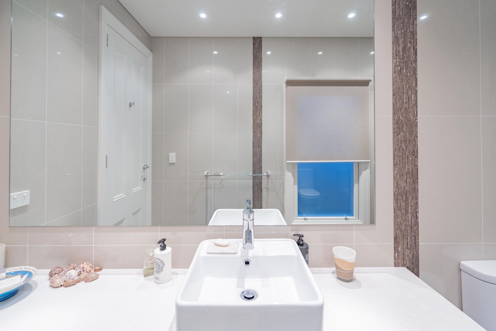 Bright bathroom with a large mirror, white sink, and a blue towel by the window. — The Plumbing & Drainage Co. in Bowral, NSW