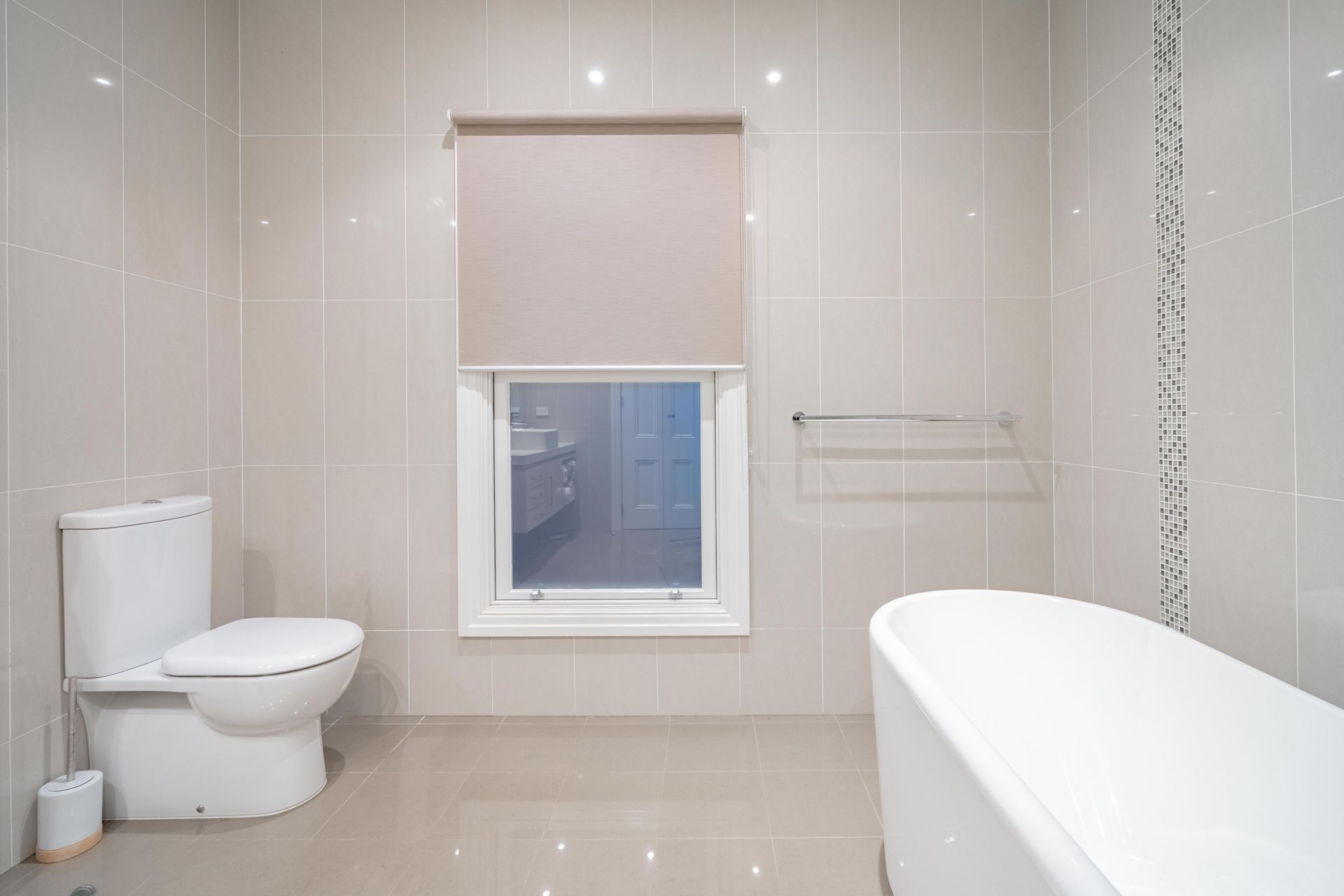 Bright modern bathroom with toilet, bathtub, window, and towel rack — The Plumbing & Drainage Co. in Bowral, NSW