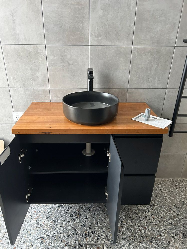 Open Bathroom Vanity With Black Sink, Wooden Top, and Cabinet Doors — The Plumbing & Drainage Co. in Mittagong, NSW