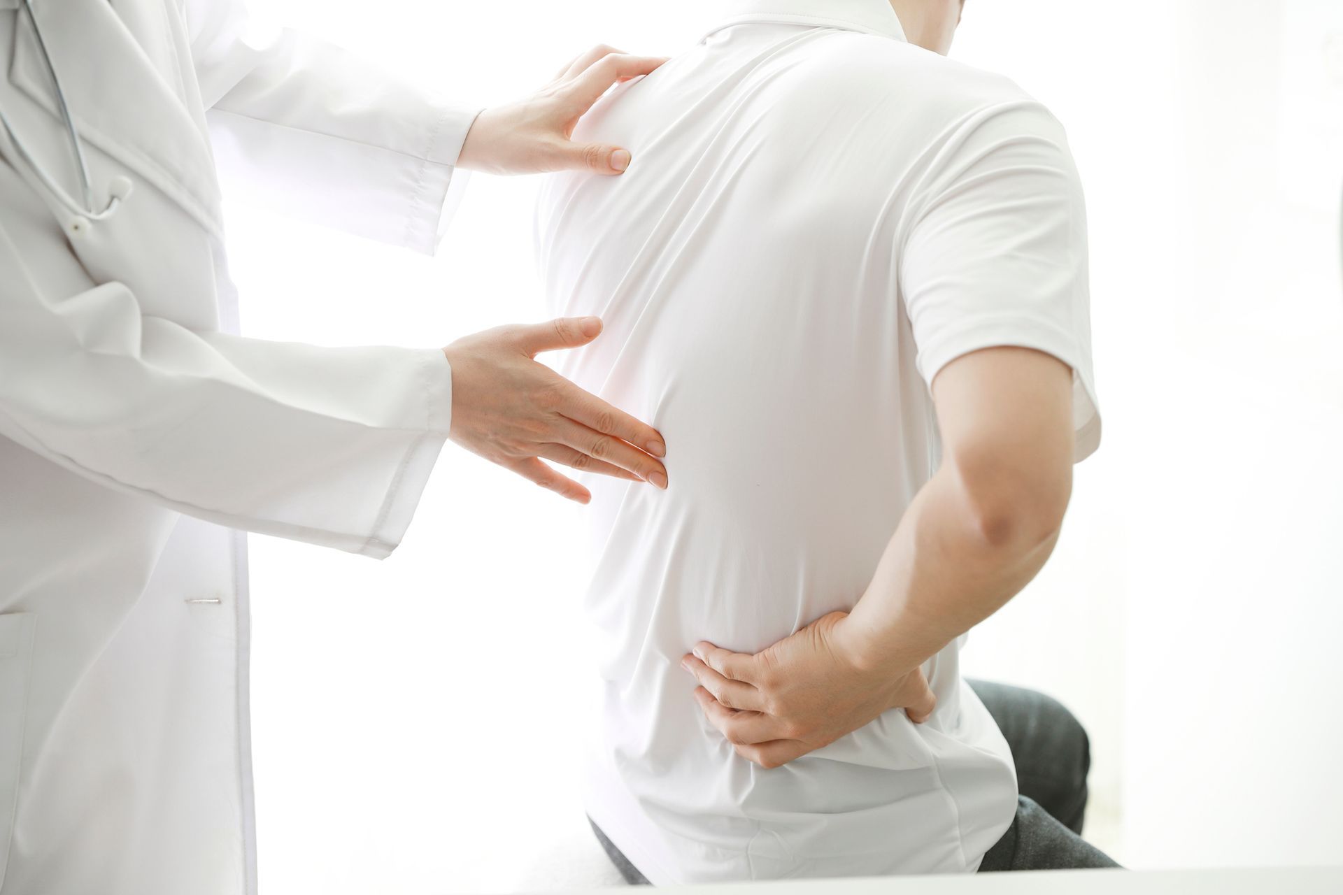 A doctor is examining the back of a patient who is having back pain — Monroe, LA — Coleman Chiropractic Clinic