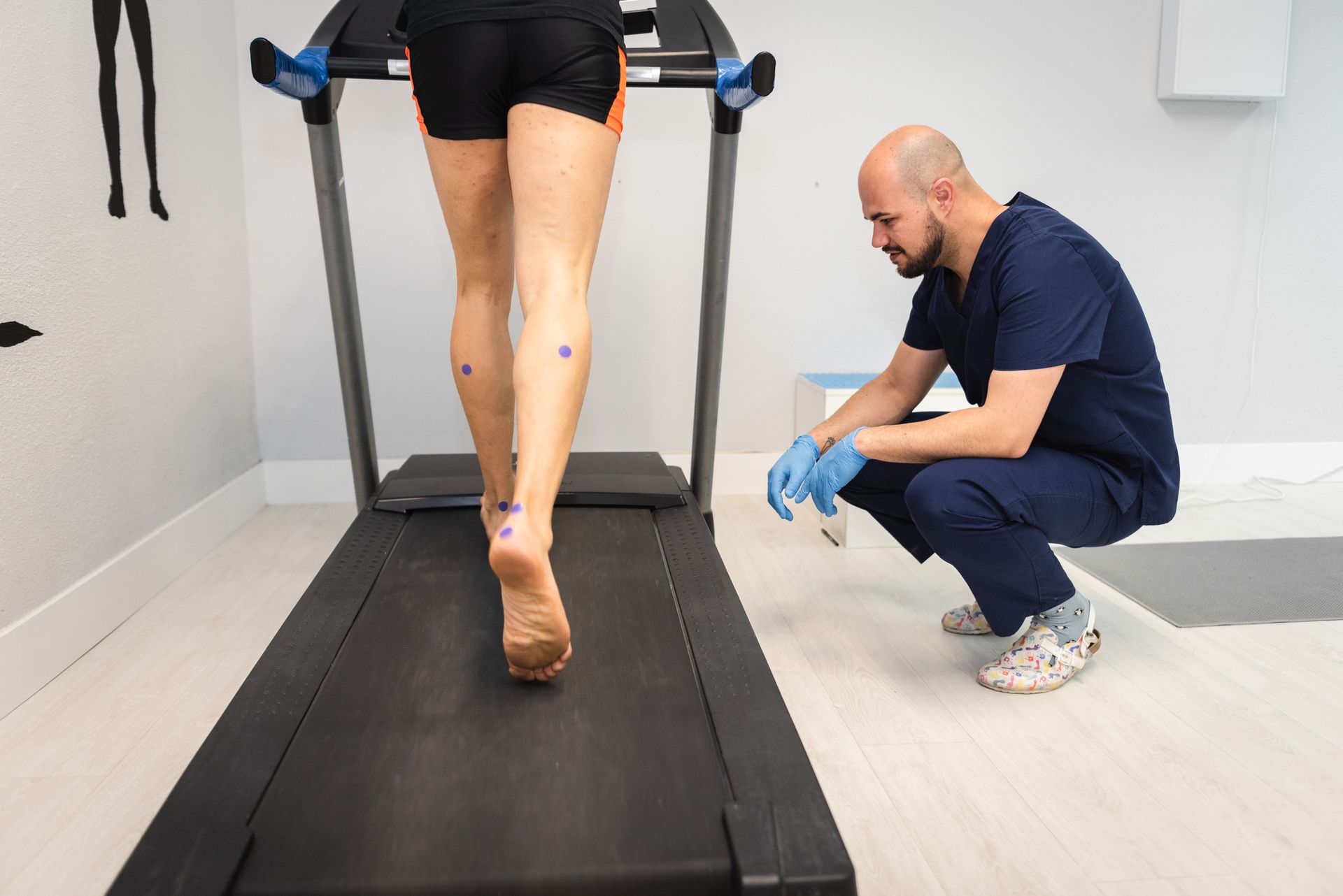 A man is examining a woman's foot on a treadmill — Monroe, LA — Coleman Chiropractic Clinic