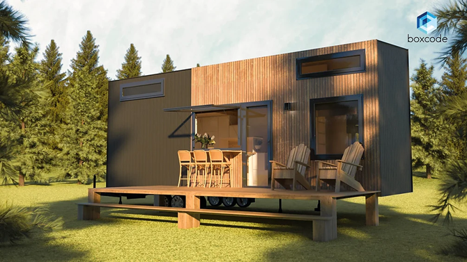 Tiny wooden home with deck and outdoor seating in a forest setting.