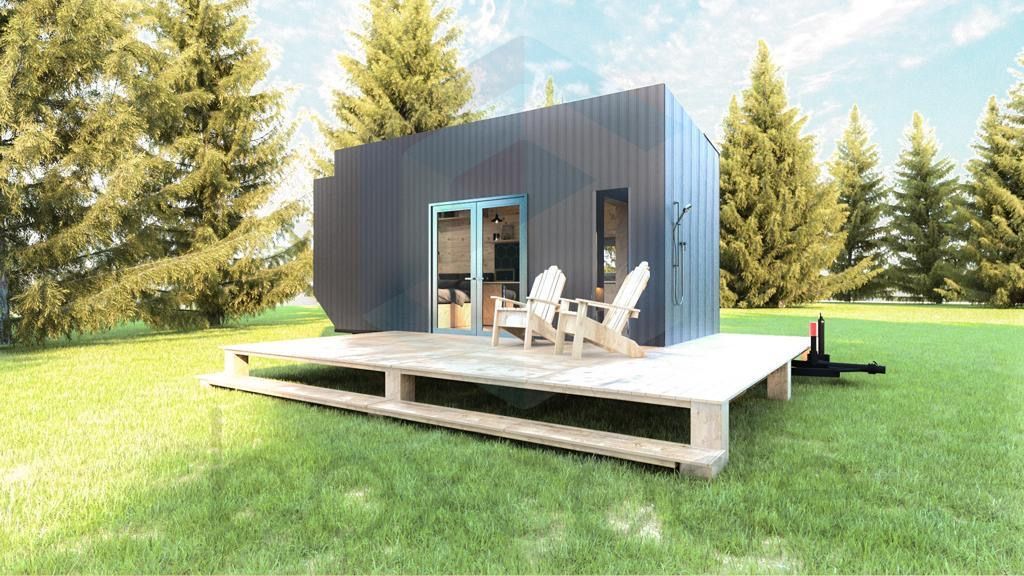 Tiny home with dark siding, deck, and two chairs on a grassy lawn.