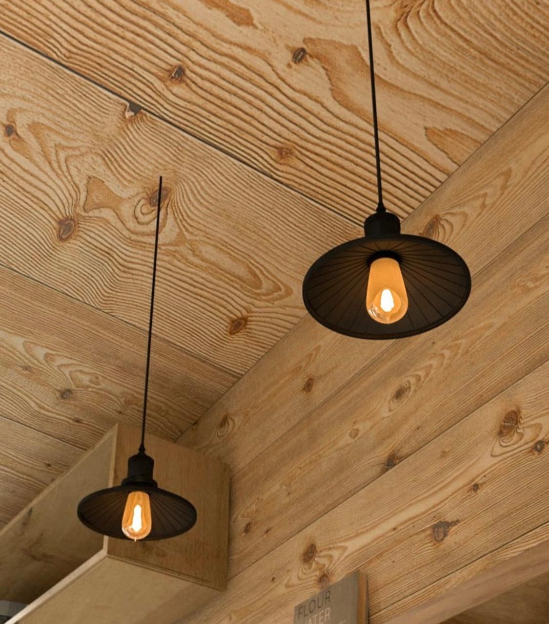 Two black pendant lights with exposed Edison bulbs hang from a wooden ceiling.