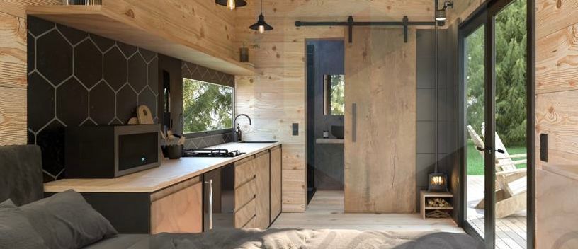 Tiny home interior with a kitchen, bathroom, and an open door to the outdoors.