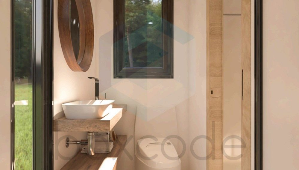 Bathroom with a white sink on wooden counter, circular mirror, and toilet. A window offers natural light.