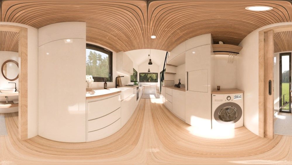 A modern, bright tiny home interior with wood ceiling, white cabinets, and a washing machine.