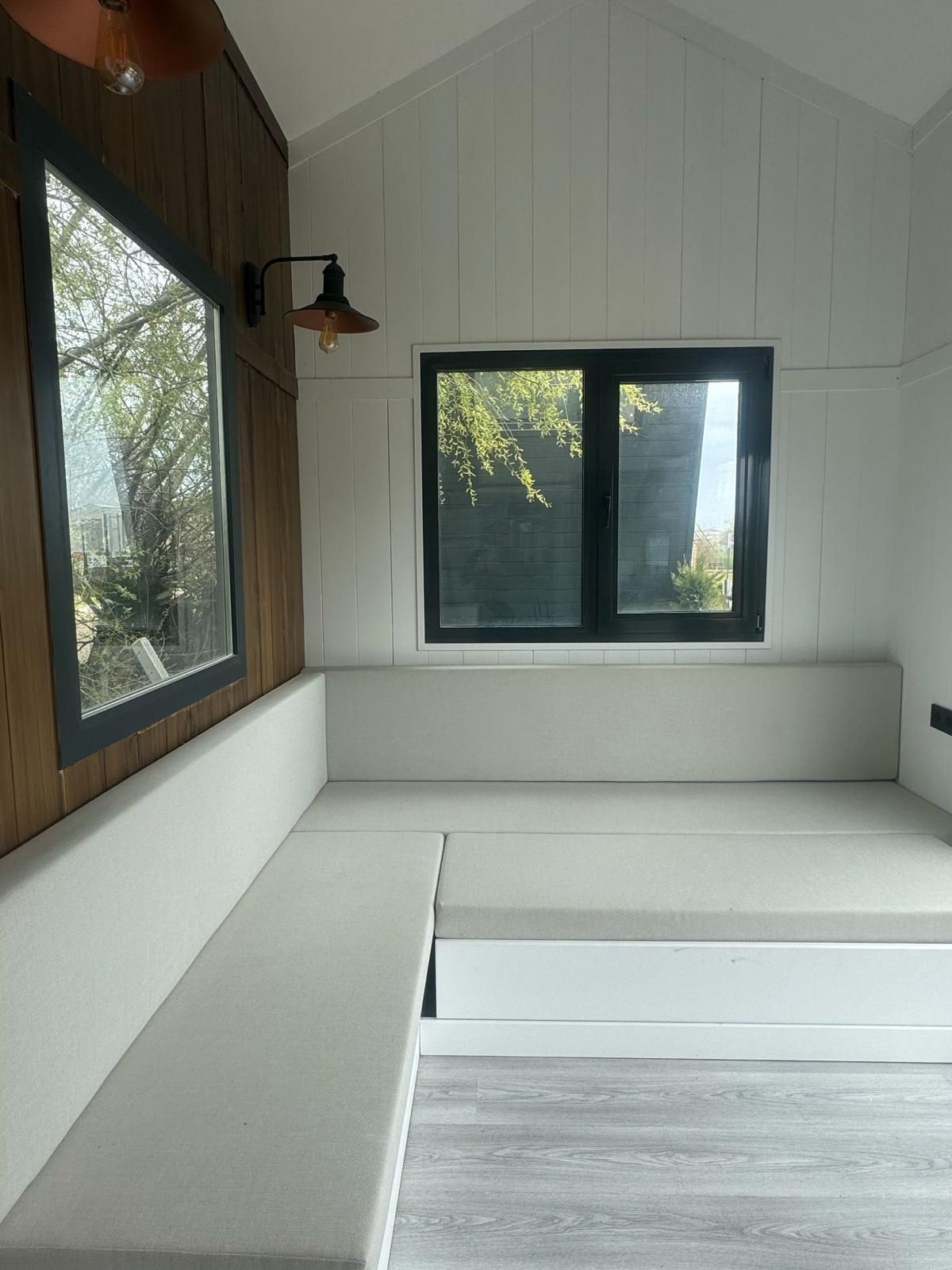 Interior with white seating, windows, and wood paneling; a modern, bright space.