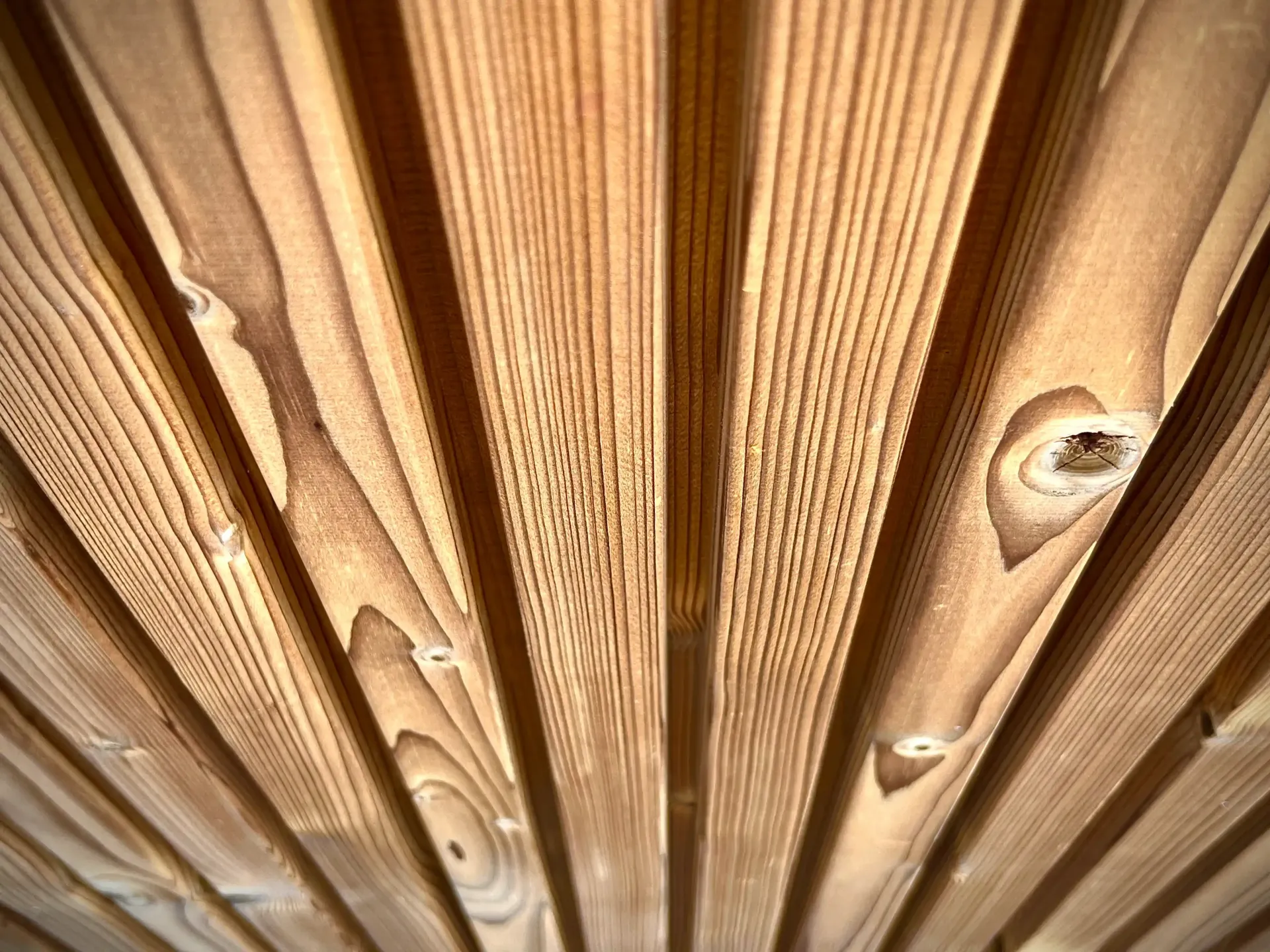 Wooden planks arranged in parallel lines, with knots and natural wood grain visible.