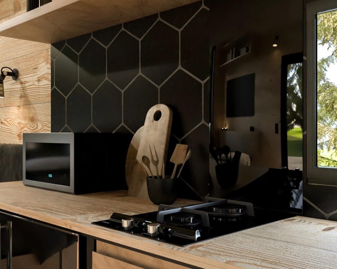 Modern kitchen with black hexagonal backsplash, wood countertop, and black appliances.