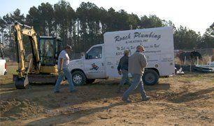 Men near Roach Plumbing truck and excavator at a construction site. Men near Roach Plumbing truck and excavator at a construction site.