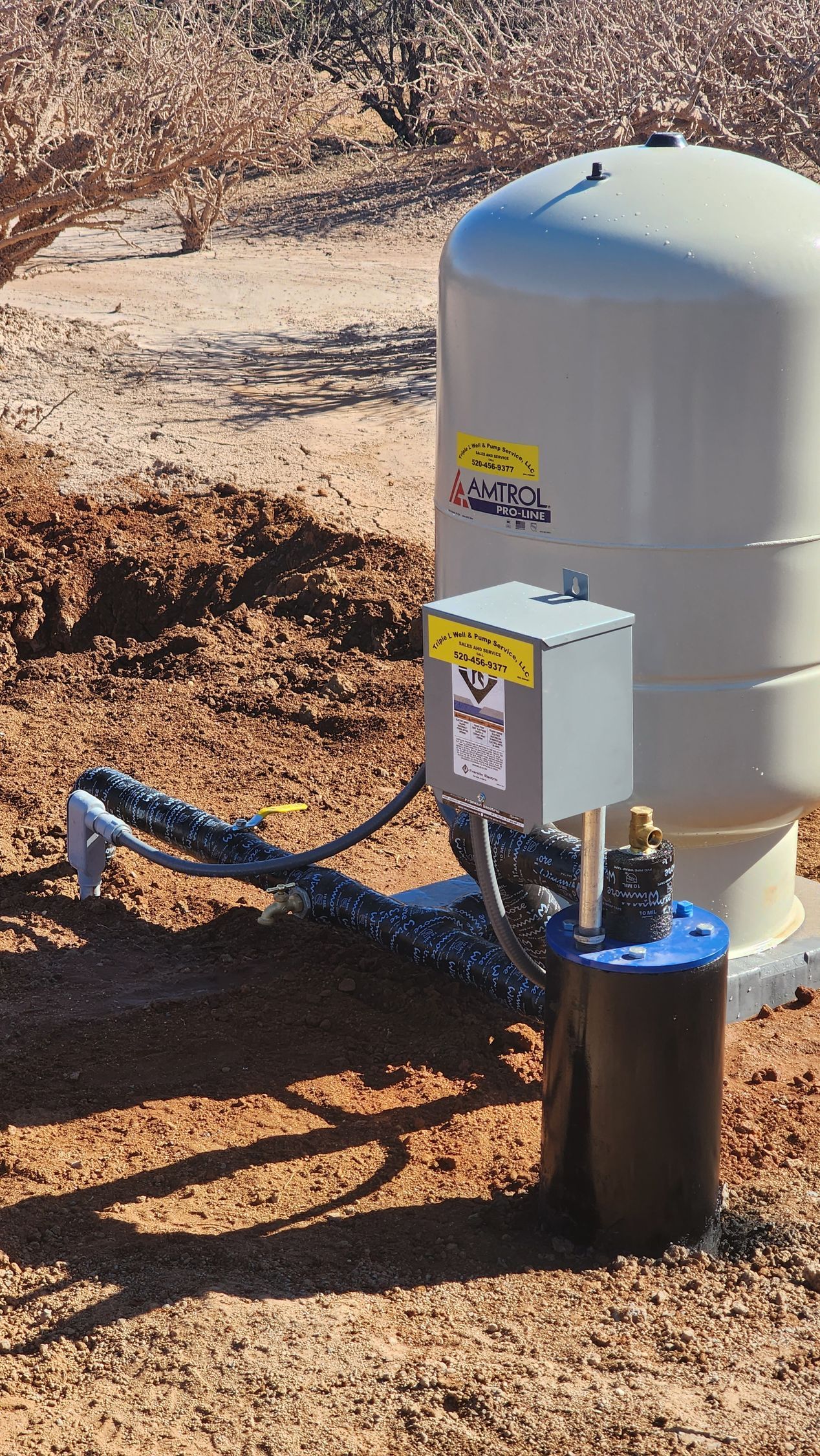 a water pump is sitting in the middle of a dirt field .