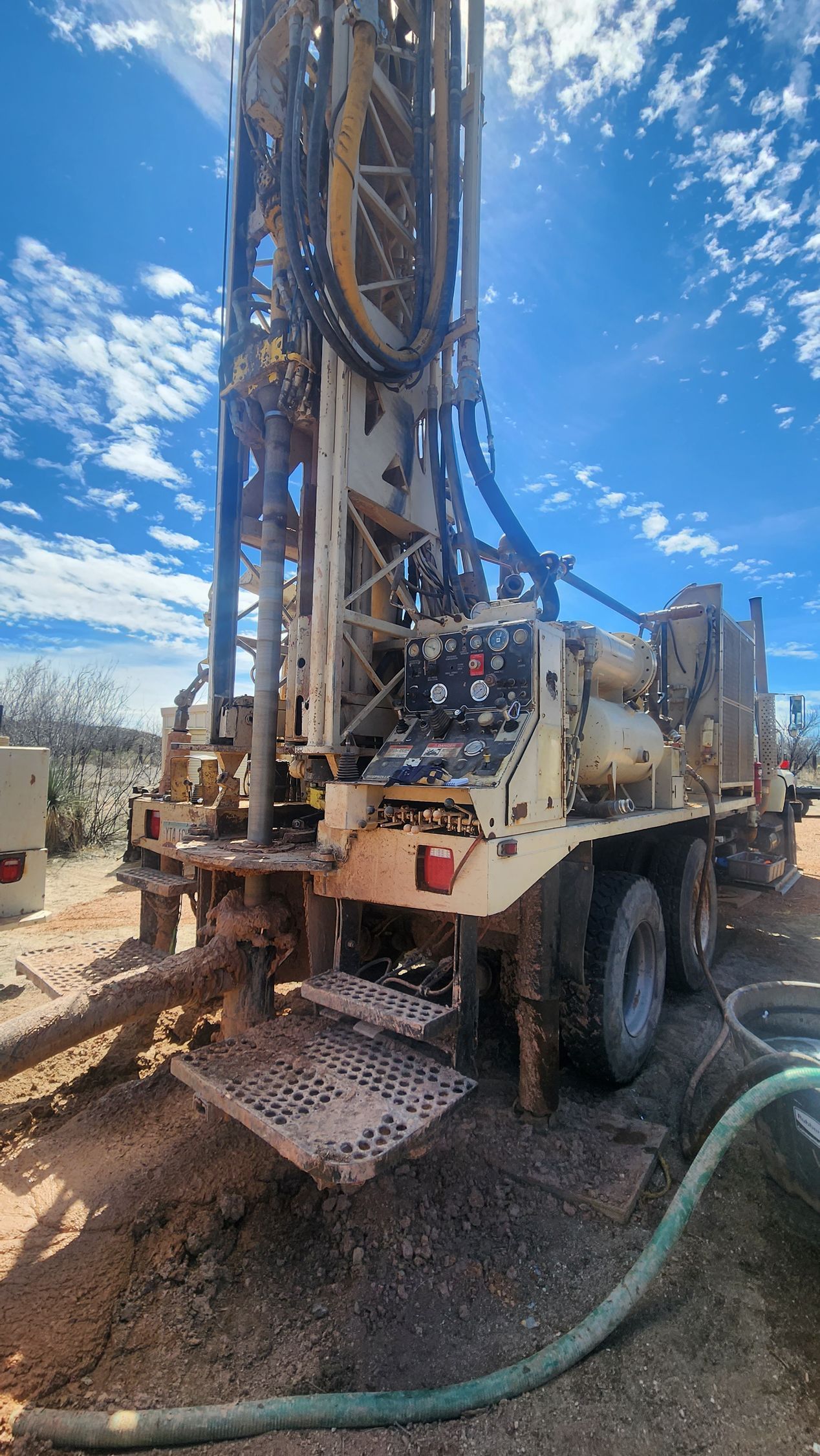 a large truck is sitting on top of a dirt field with a hose attached to it .