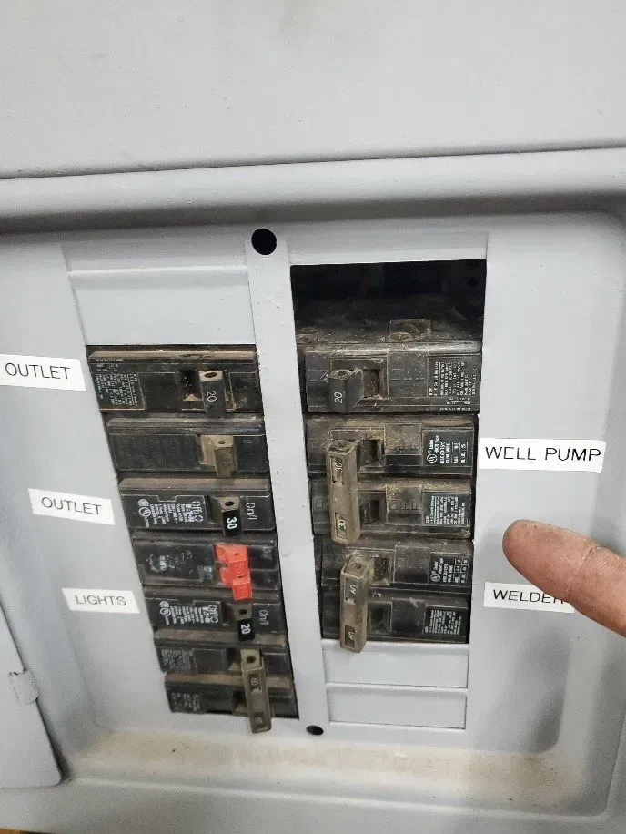 a person is pointing at a breaker on a electrical box .