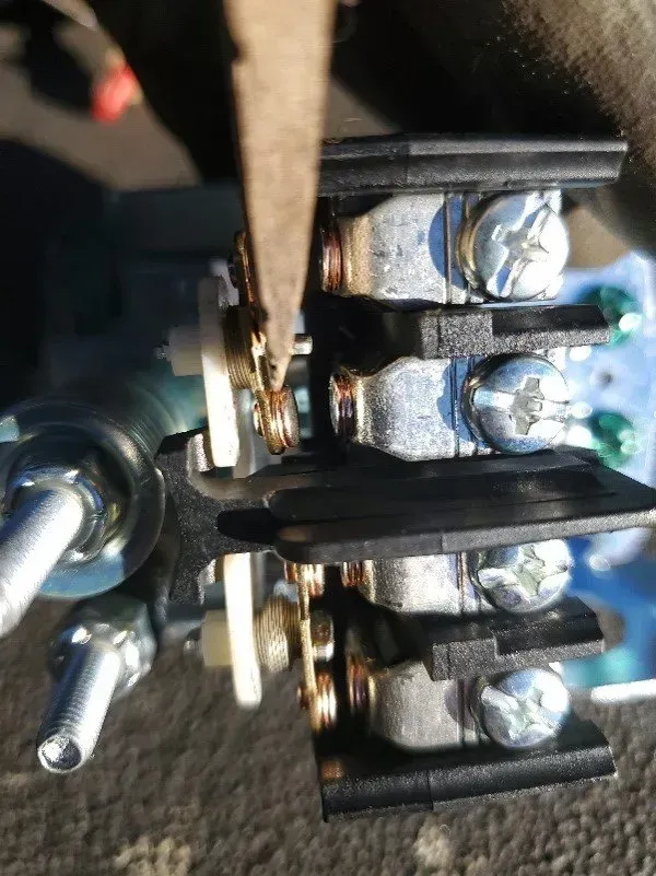 a pair of pliers is being used to remove a screw from a switch .