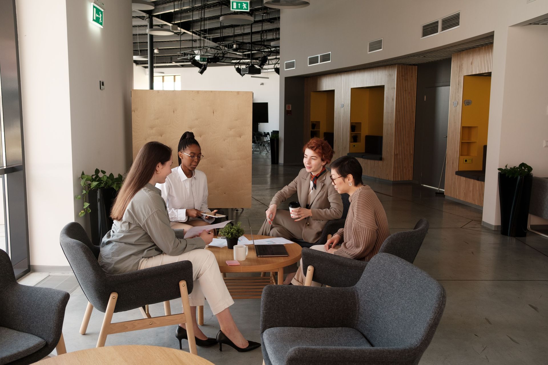 Four people chatting around a coffee table in a modern office lounge