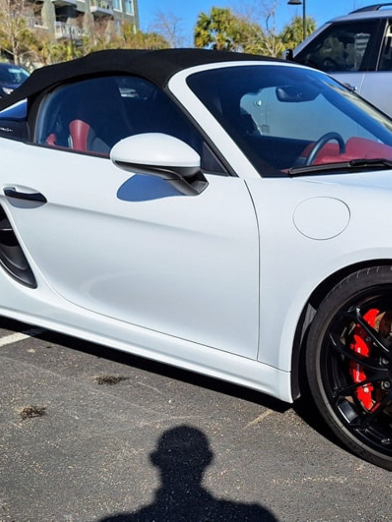 A white sports car is parked in a parking lot