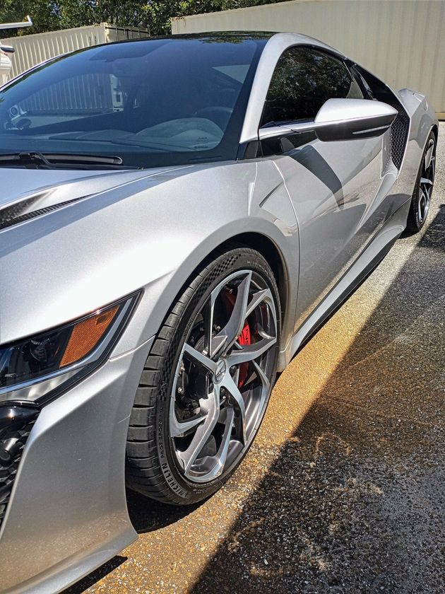 A silver sports car is parked on the side of the road.
