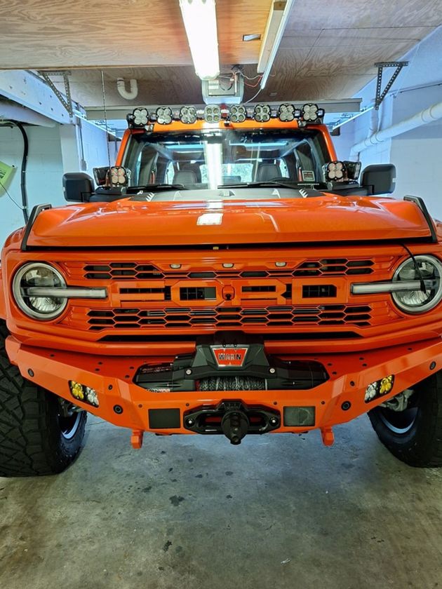 An orange ford bronco is parked in a garage.