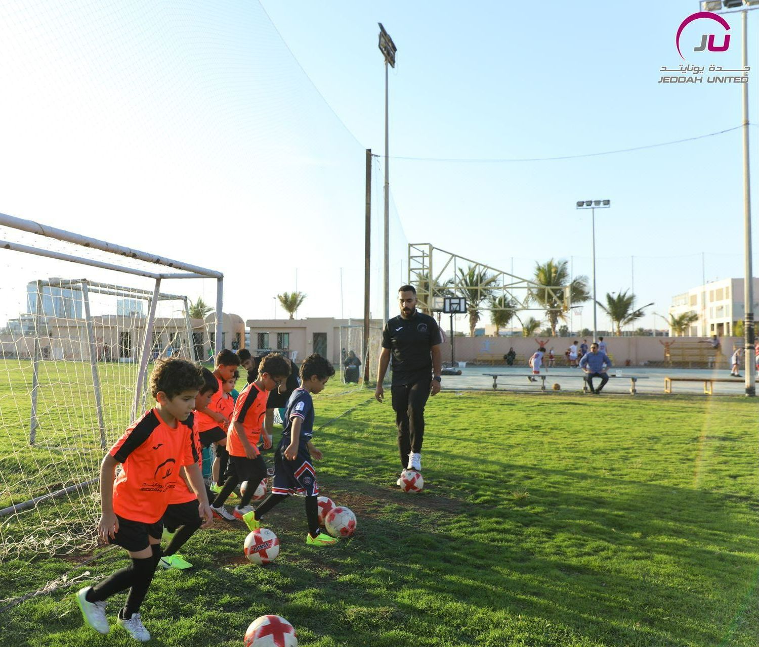 A coach teaching young boys football in JU A coach teaching young boys football in JU