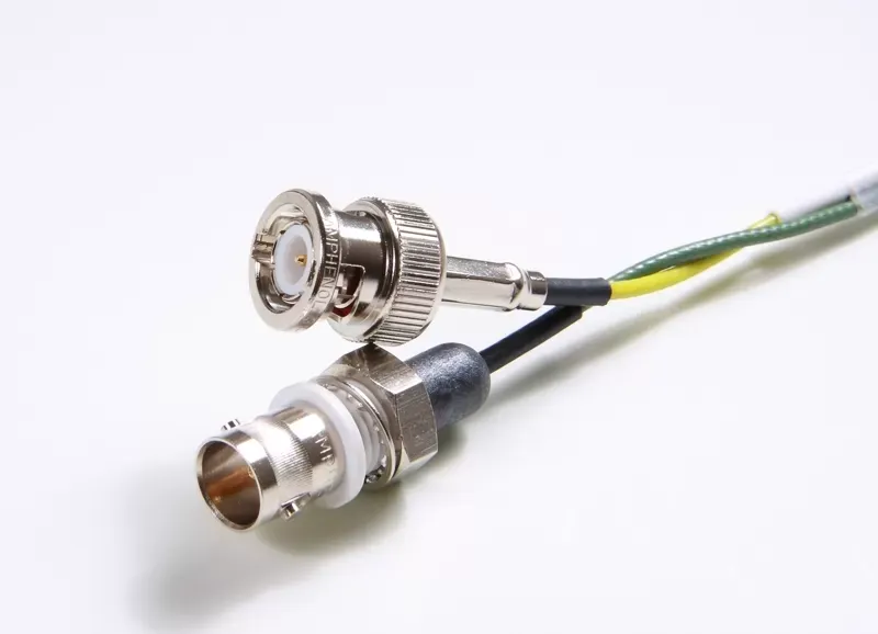 Two BNC connectors with attached black, yellow, and green wires against a white background.