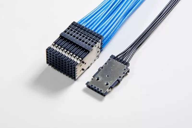 Two electronic cable connectors: one large with blue wires and one small with black wires, resting on a white background.