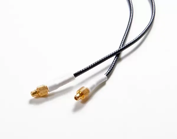A black coaxial cable with two gold-colored SMA male connectors and white heat-shrink tubing on a white background.