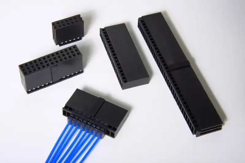 Assorted black electrical connector blocks on a white background, one attached to blue wires.