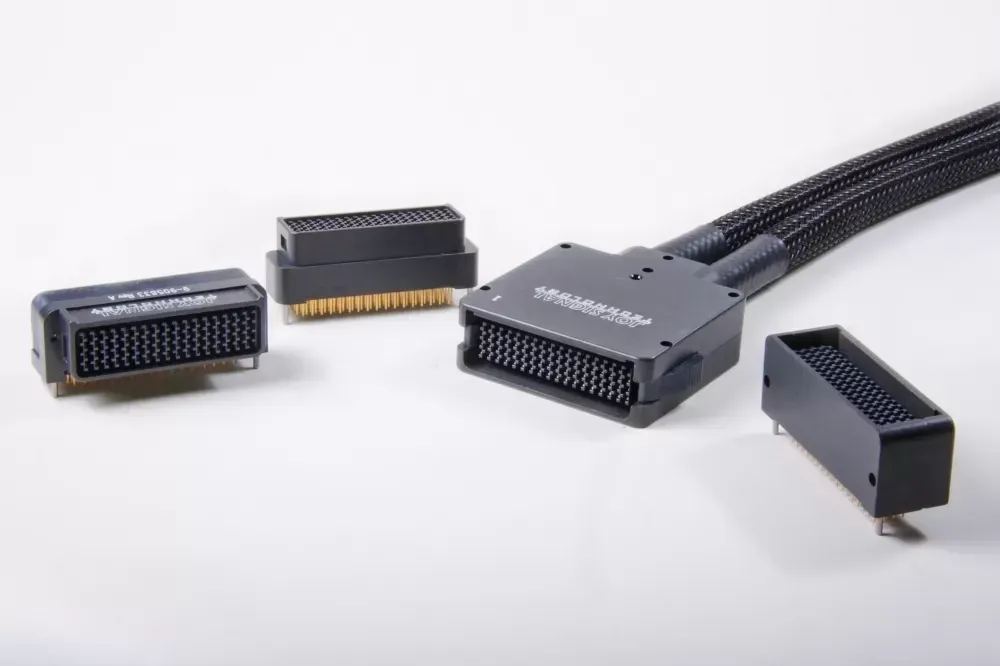 Four black electronic multi-pin connectors are arranged on a white background, with one attached to a braided cable.