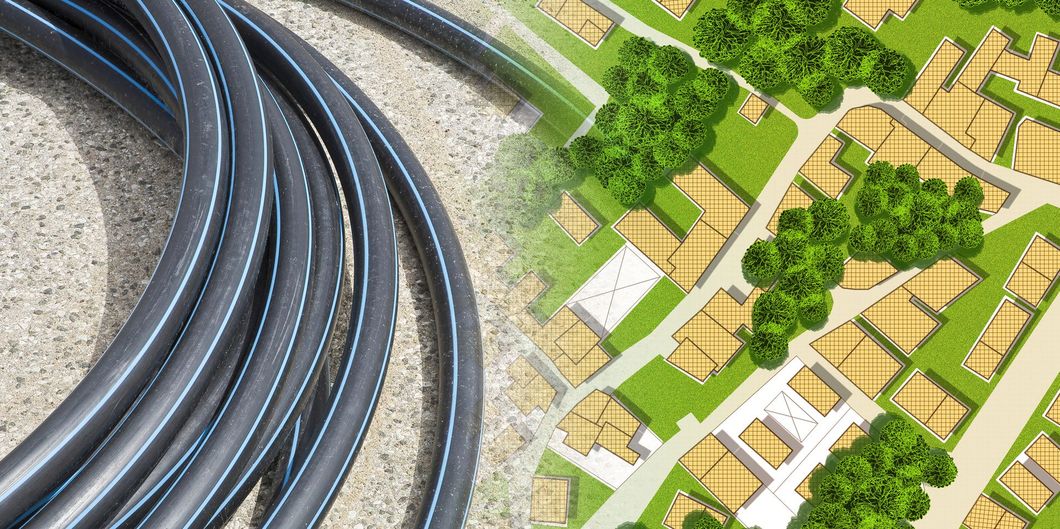 Binari neri curvi accanto a un piccolo villaggio ferroviario immerso nel verde, con alberi ed edifici.