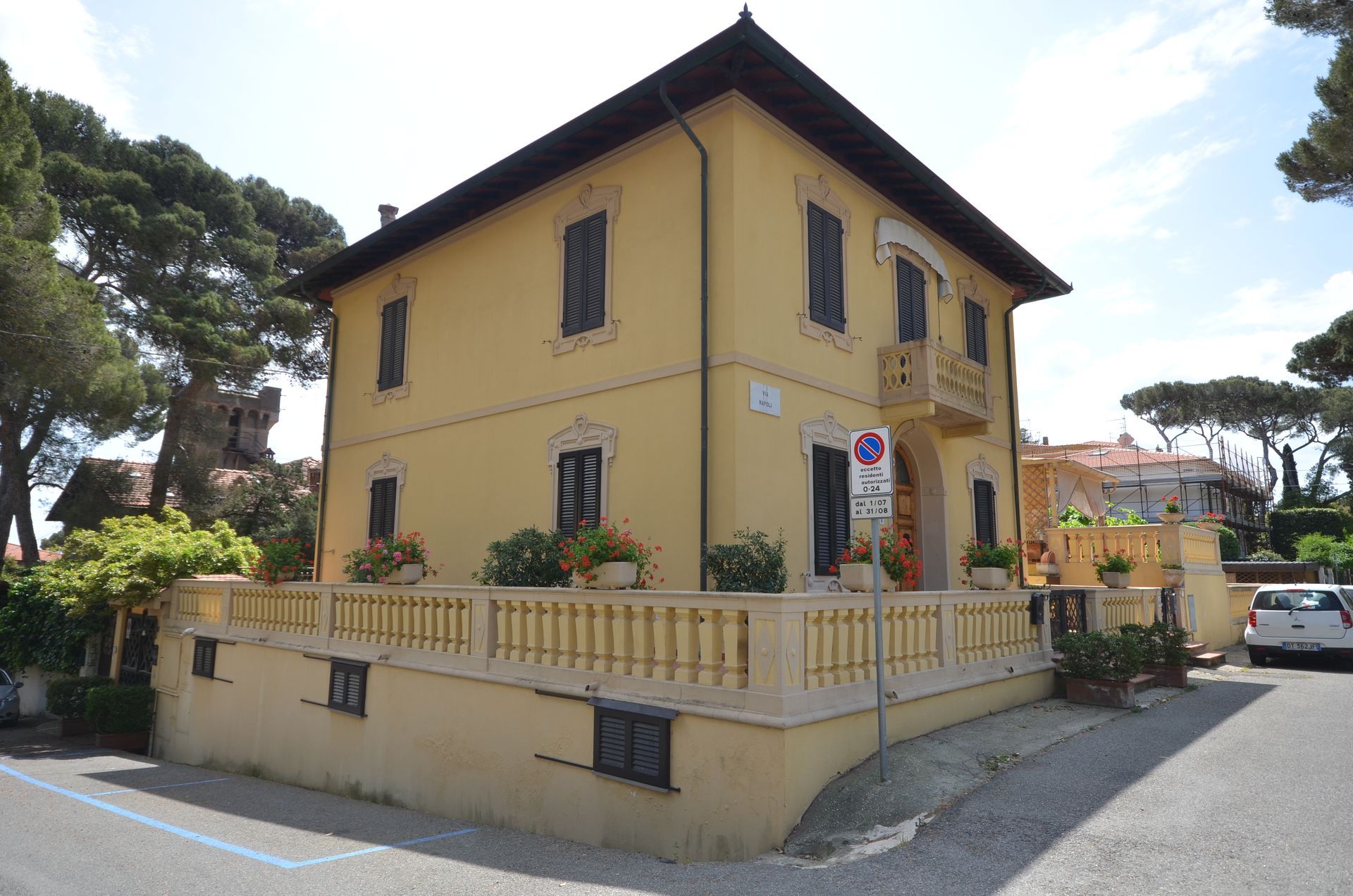 Casa gialla a due piani con tetto di tegole e balcone, situata in una strada tranquilla.