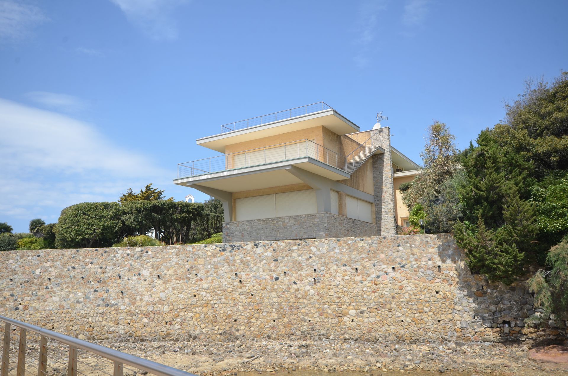 Edificio giallo su un terrapieno di pietra sotto un cielo azzurro limpido, visto dal basso.