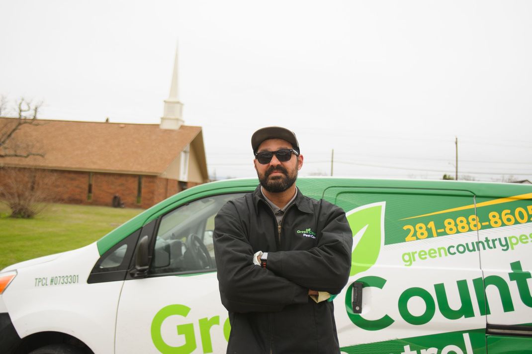Man in uniform standing in front of a green van with company logo 