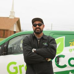 Man in sunglasses, arms crossed, stands next to a green van with 
