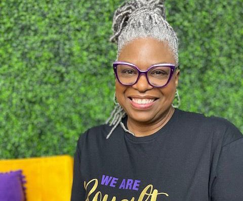 A woman wearing glasses and a black shirt is smiling for the camera.