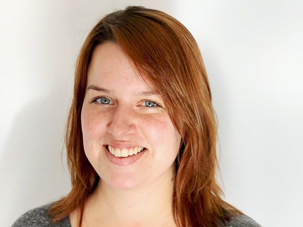 Shelby Withiam with auburn hair and blue eyes, positioned against a plain, light background.