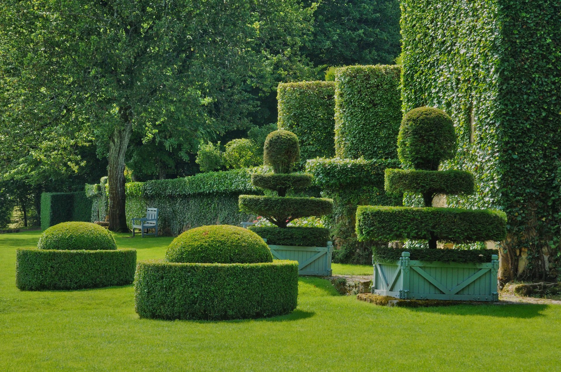 Giardino ornamentale curato nei minimi dettagli, con siepi potate e prato verde, in un contesto di parco formale.
