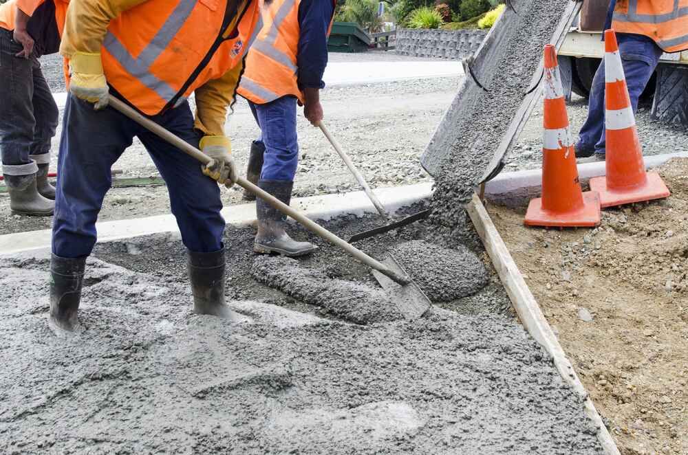 A Group Of Construction Workers Are Pouring Concrete On A Sidewalk — Clearspan Builders In Queanbeyan, NSW
