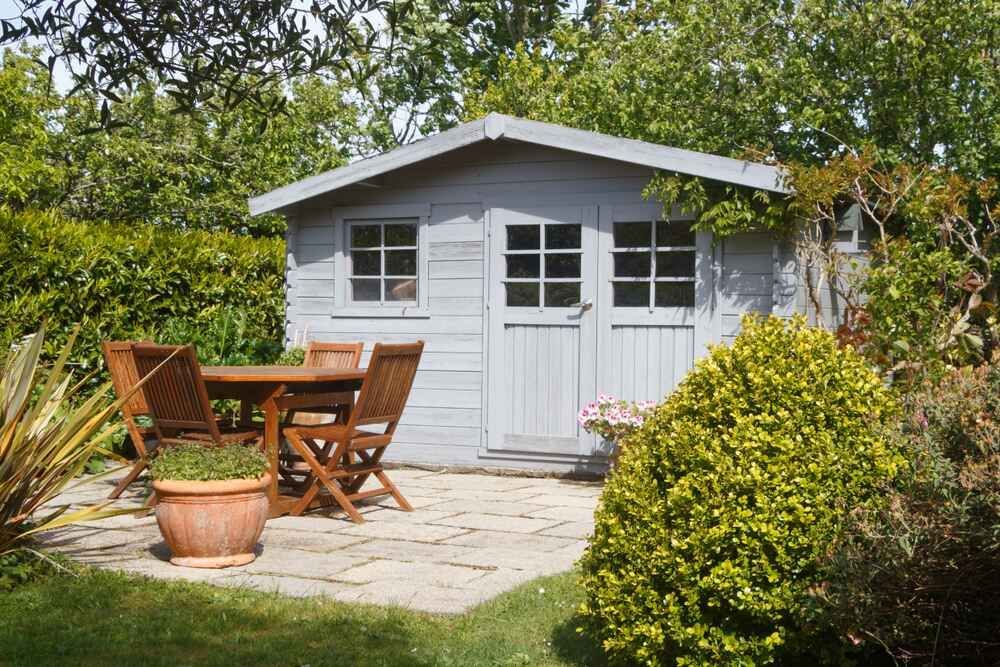 A Garden Shed With A Table And Chairs In Front Of It — Clearspan Builders In Canberra, ACT
