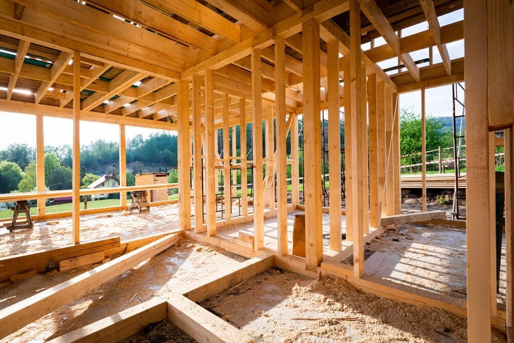 Wooden Frame of a House Under Construction, With Sunlight Streaming Through Walls — Clearspan Builders In Braidwood, NSW