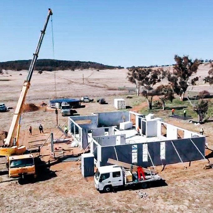 A Construction Site With A Crane And Trucks Surrounding It And A Mountain In The Background— Clearspan Builders In Queanbeyan East, NSW
