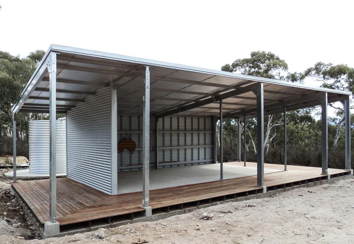 A Large Metal Structure with A Wooden Deck in Front of It — Clearspan Builders In Queanbeyan East, NSW