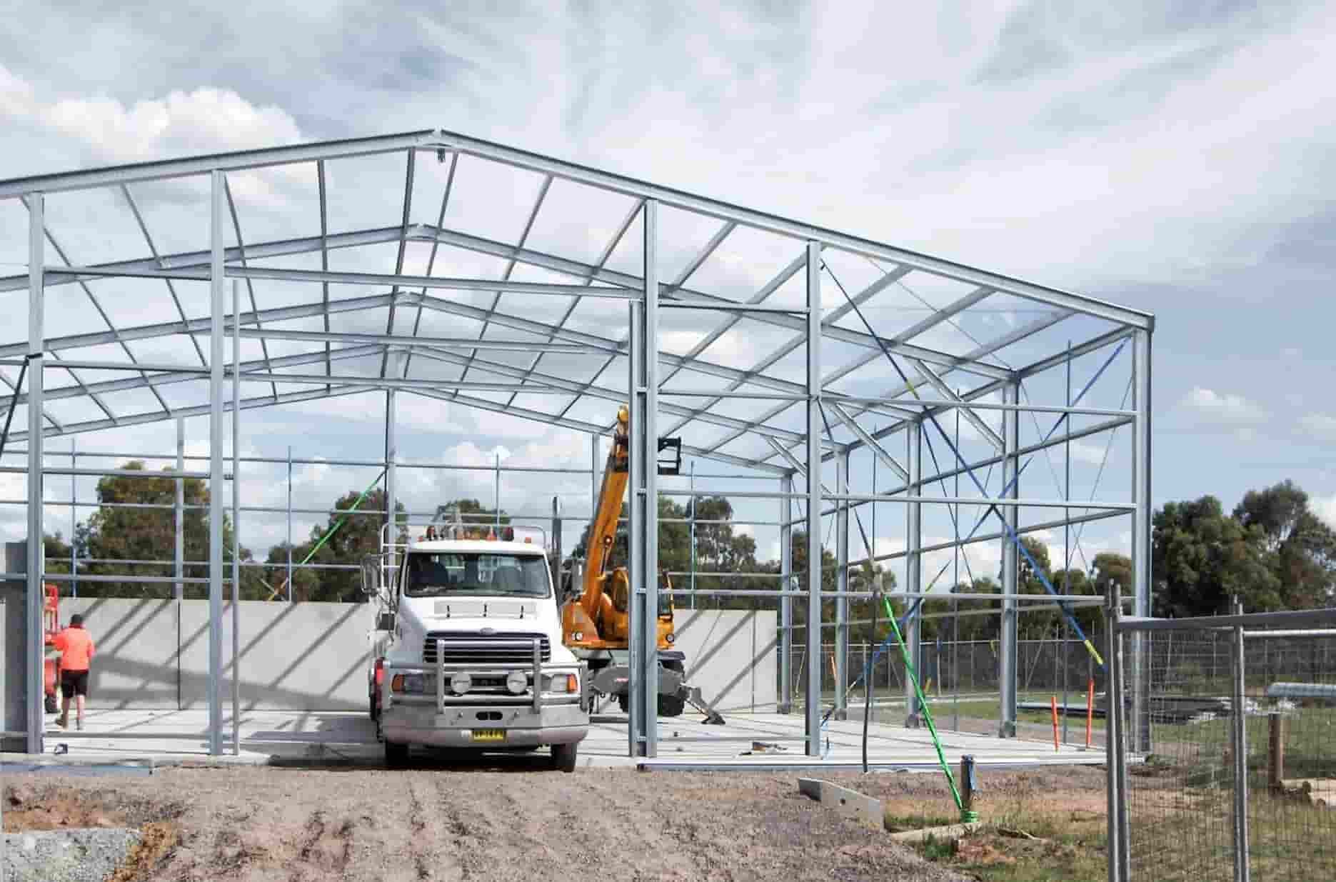 A Truck and Bulldozer Are Parked Underneath A Shed Being Built — Clearspan Builders In Queanbeyan East, NSW